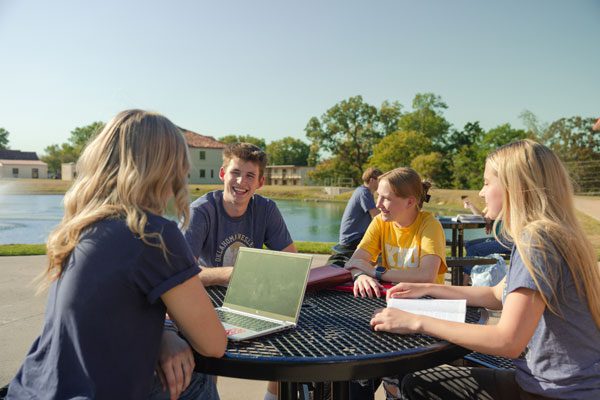 Group of students sitting at a table by the pond