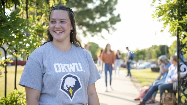 Student smiling and walking near campus landmark