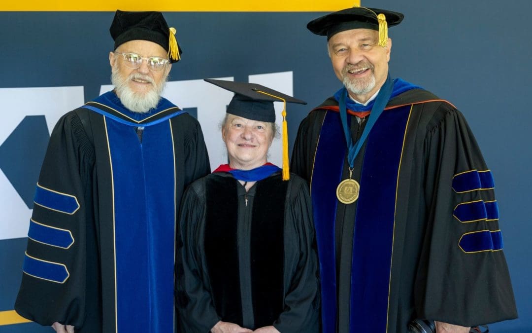 Professors in front of sign