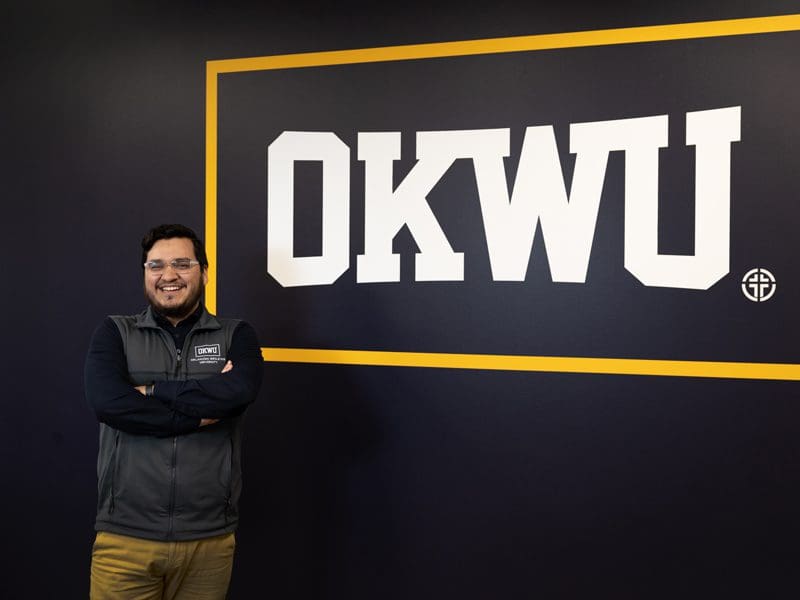 Photo of admissions counselor by OKWU sign